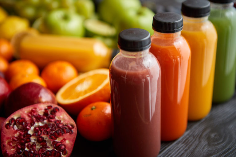 Colorful bottles filled with fresh fruit and vegetable juice or ...